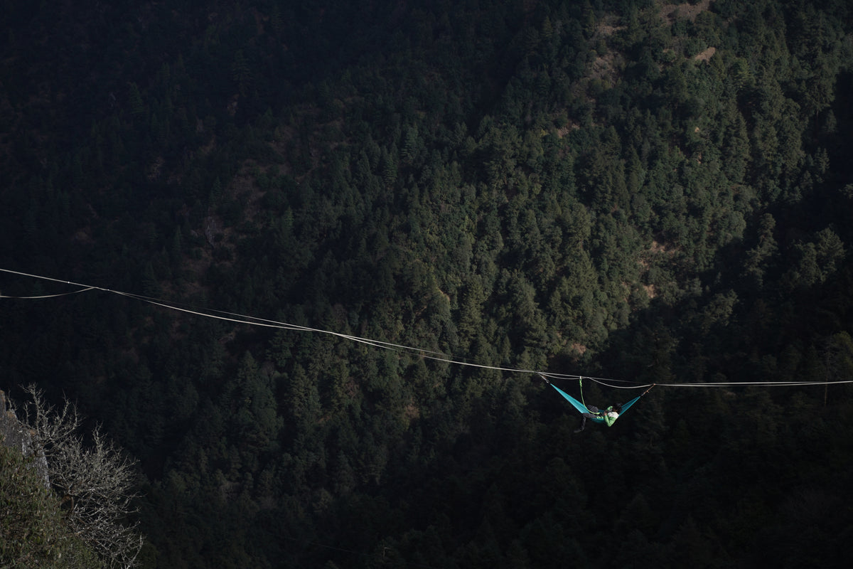 Someone lying back in a Yachu hammock on a highline above the forest at Bethanchowk, 3,000 m