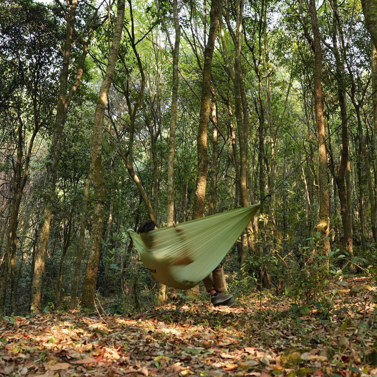 Backpacker relaxing in ultralight hammock at camp