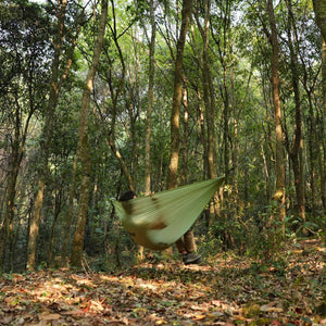 Backpacker relaxing in ultralight hammock at camp